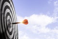 Red arrow dart hit to center of target board with cloud sky background. Business investment target concept