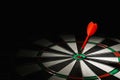 Red arrow hitting target on dart board against black background Royalty Free Stock Photo