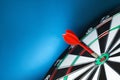 Red arrow hitting target on dart board against blue . Space for text Royalty Free Stock Photo