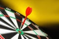 Red arrow hitting target on dart board  yellow background. Space for text Royalty Free Stock Photo