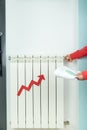 Red arrow of price increase on heating radiator. Woman with bill closes heating. Vertical photo