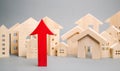 Red arrow up and miniature wooden houses. The concept of rising property prices. High mortgage rates. Expensive rental apartment. Royalty Free Stock Photo