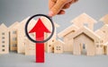 Red arrow up and miniature wooden houses. The concept of rising property prices. High mortgage rates. Expensive rental apartment. Royalty Free Stock Photo