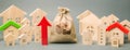 Red arrow up, money bag and miniature wooden houses. The concept of rising property prices. High mortgage rates. Expensive rental Royalty Free Stock Photo