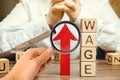 Red arrow up near wooden blocks with the word Wage and a businessman. Salary increase concept. Wages rate. Revenue growth and