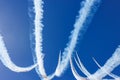 The Red Arrows perform aerobatic maneuvers against a bright blue sky with white vapour trails Royalty Free Stock Photo