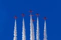 The Red Arrows perform aerobatic maneuvers against a bright blue sky with white vapour trails Royalty Free Stock Photo