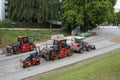 Red asphalt paving machines such as street rollers and wheel dozer are parked on the street.