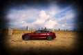 Red Audi A5 Sportback car parked on a sandy terrain with a cityscape in the background Royalty Free Stock Photo