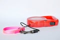 Red automatic leash and pink nylon dog collar on white background