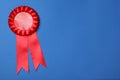 Red award ribbon on blue background, top view. Space for text Royalty Free Stock Photo