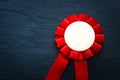 Red award rosette with ribbons over black textured background, ready for mock up