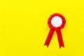 Red award rosette with ribbons over yellow textured background, ready for mock up