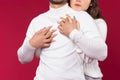 Red background. Enlarged photo of an embrace where girl`s hands hug her soulmate, white sweater. Love on Valentine`s Day