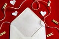 A red background from felt. A composition from heart, thread and clothespins. Frame from envelope for writing. Background with