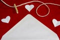 A red background from felt. A composition from heart, thread and clothespins. Frame from envelope for writing. Background with