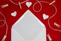 A red background from felt. A composition from heart, thread and clothespins. Frame from envelope for writing. Background with