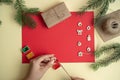 On a red background fir-tree branches and wooden Christmas toys, snowman with gifts. Christmas greeting card, concept diy. Royalty Free Stock Photo