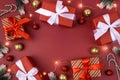 Red background with gifts, decorations, christmas garland and candy cane. Place for text. Xmas flat lay with fir branches.