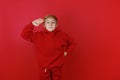 on a red background stands a boy dressed in a red suit who put his hand to his head Royalty Free Stock Photo