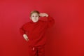 on a red background stands a boy dressed in a red suit who put his hand to his head Royalty Free Stock Photo