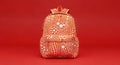 Red backpack with white polka dots standing upright against a vibrant solid red background with studio lighting for a bold visual Royalty Free Stock Photo