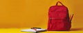 Red backpack on yellow background, back to school concept