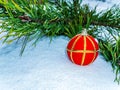 Red ball Christmas tree toy with gold edging on the snow. Royalty Free Stock Photo