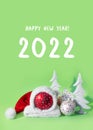 Red ball in  hat of santa claus with white spruce tree on green background. The symbol of new year and christmas Royalty Free Stock Photo