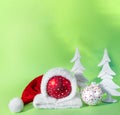 Red ball in  hat of santa claus with white spruce tree on green background. The symbol of new year and christmas Royalty Free Stock Photo