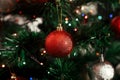 red ball ornament close up. decorating christmas tree at home for holiday season on background of tree with colorful lights. Royalty Free Stock Photo