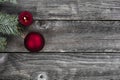 Red ball ornament plus burning candle and fir decorations on vintage wooden planks for a merry Christmas or happy New Year holiday Royalty Free Stock Photo