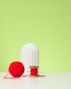 Red ball with woolen thread and large needle on white table, green background Royalty Free Stock Photo