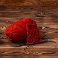 Red ball of yarn and knitting needles with knitting on wooden background