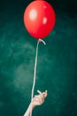 red balloon in hand on a green background flies up close-up