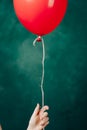 red balloon in hand on a green background flies up close-up