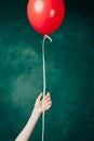 red balloon in hand on a green background flies up close-up