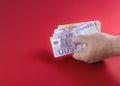 Red banner with cash money in a man's hand on a red table background. Hand holding euro banknotes. Red background Royalty Free Stock Photo