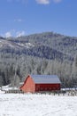 Red barn under a blue sky in winter.