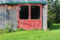 Red barn doors with large windows in green track on a weathered wood building Royalty Free Stock Photo