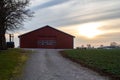 A red barn at the end of a gravel road in a farm landscape in southern Sweden SkÃÂ¥ne, Scania during dusk on a cold winter day Royalty Free Stock Photo