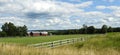 Red barns, wood fence, green pasture, blue sky
