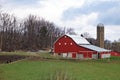 Red barn in a green field near the bare trees