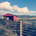 Red barn on hillside with lake, hills and sky background Royalty Free Stock Photo
