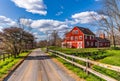 Red barn and horse fence along country road Royalty Free Stock Photo