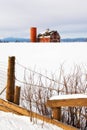 Red Barn in the snow with a rustic fence Royalty Free Stock Photo