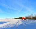 Red barn on snowy winter hill under a blue sky Royalty Free Stock Photo