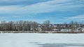 Red barn between trees on a cloudy winter day in Colorado with frozen lake in foreground Royalty Free Stock Photo