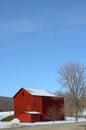 Red barn in winter countryside and blue sky above Royalty Free Stock Photo