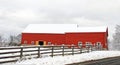 red barns and wooden property fence at roadside covered in fresh Winter white snow Royalty Free Stock Photo